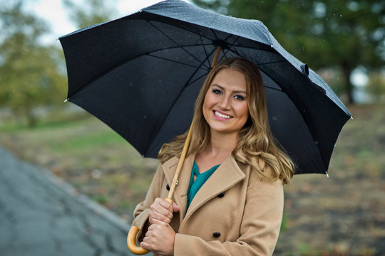 Portrait of a young woman holding an umbrella in the rain.