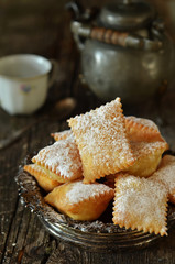 Chiacchiere in a rustic bowl on a wooden background