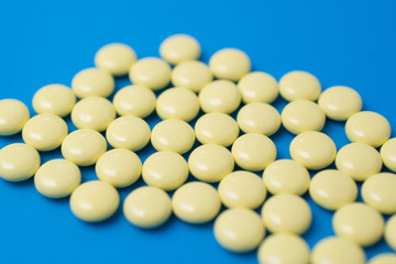 Yellow pills on blue background, painkiller or antibiotic concept