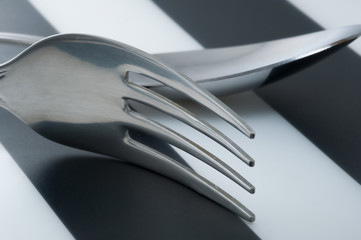 Fork and spoon laying next to each other on striped black and white 