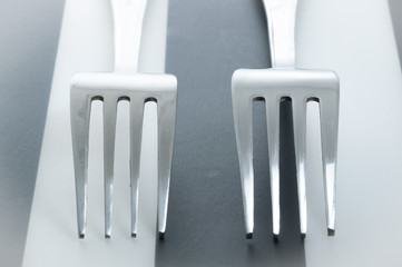 Two forks cross on striped background. 2 forks laying next to each other.