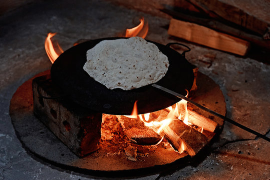 Pita bread baking on a saj or tava on  fire, close-up.