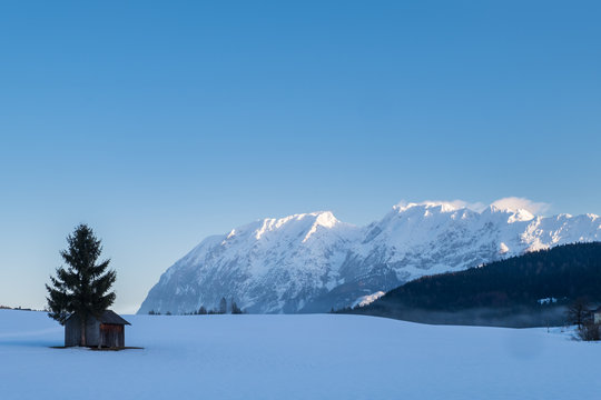 Snow covered hut on field with mountains Grimming, Schartenspitze, Steinfeldspitze