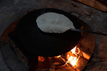 Pita bread baking on a saj or tava on fire, close-up