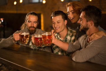 Pretty female client smiling and spending time with friends. Company of handsome man and beautiful red haired woman resting in beer pub. Concept of beer.