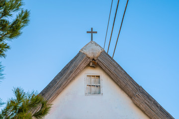 Cross on the old Thatched  roof. Clean facade and window under the roof.