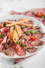 Meat antipasto on a large plate with breadsticks. Restaurant feed.