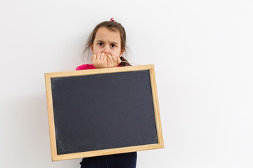 Cute little girl holding a chalkboard, isolated on white