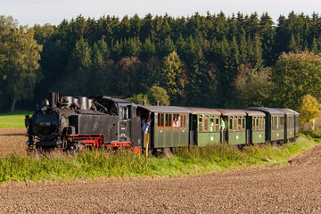 Schmalspur Dampflokomotive während der Fahrt in freier Landschaft