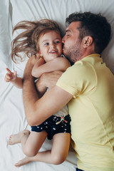 Father and daughter playing on bed