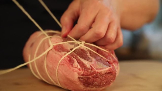 Close up, tying twine around beef tenderloin