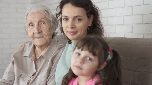 Granddaughter mother grandmother together sitting. Three generations of women in the same family.