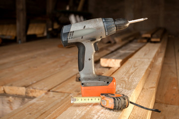 Cordless drilling tool using to build a wooden house. Construction tool close-up background.