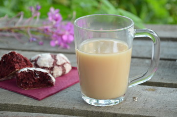 Red velvet cookies next to a cup of coffee. sunny spring or summer morning. pink purple flower