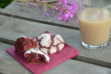 Red velvet cookies next to a cup of coffee. sunny spring or summer morning. pink purple flower