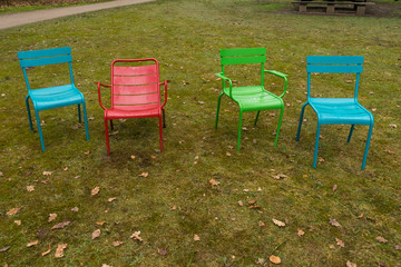 4 color charis red, blue, green empty furniture. standing outside on the ground. In the grass in an outdoors park with green grass