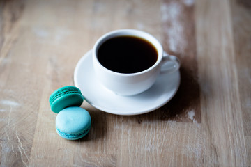 Good morning or Have a nice day message concept - white cup of coffee with colourful French macaroons on  rustic wooden background