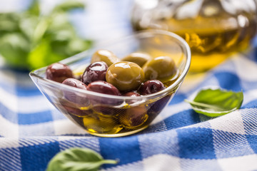 Green and red olives in bowl with olive oil and carafe in the background