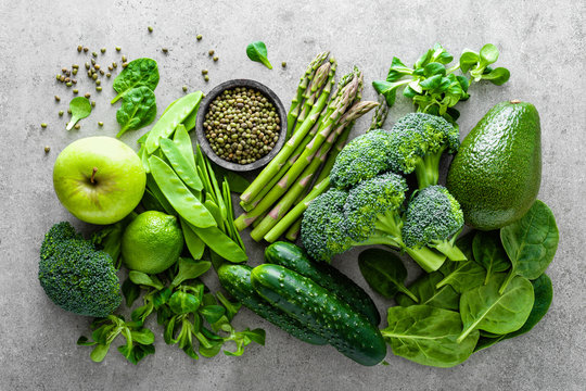Healthy vegetarian food concept background, fresh green food selection for detox diet, raw broccoli, apple, cucumber, spinach, peas, asparagus, avocado, lime, corn salad and mung bean, view from above