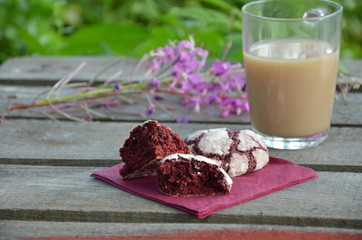 Red velvet cookies next to a cup of coffee. sunny spring or summer morning. pink purple flower