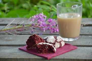 Red velvet cookies next to a cup of coffee. sunny spring or summer morning. pink purple flower