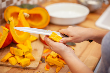 woman cut the pumpkin with a knife in her kitchen