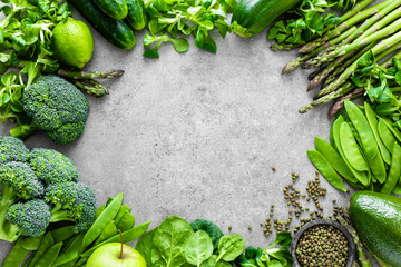 Healthy vegetarian food concept background, fresh green food selection for detox diet, raw broccoli, apple, cucumber, spinach, peas, asparagus, avocado, lime, corn salad and mung bean, view from above