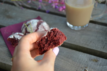 Red velvet cookies next to a cup of coffee. sunny spring or summer morning. pink purple flower