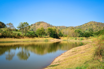 Fototapeta na wymiar Pond on summer season forest with agricultural area and mountain background sunny day blue sky