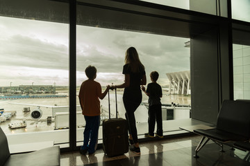 Silhouettes of mom with kids in terminal waiting for flight Travel Concept