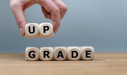 Dice built the word "UPGRADE" while a hand lifts the letters "UP"