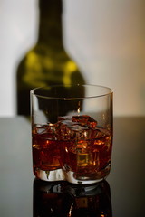 Gorgeous view of glass of alcohol drink with ice on shadow of bottle background. Beautiful backgrounds.