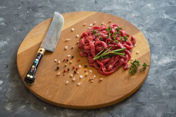Fresh meat cut into thin strips on cutting board. 