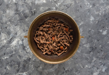 Stewed meat cut into thin strips in a cauldron.