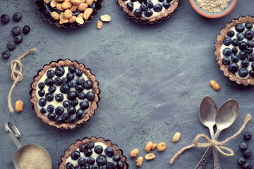 Top view on wholegrain blueberry tarts with vanilla cream on dark