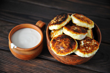 cheesecakes with sour cream in pottery on a wooden table