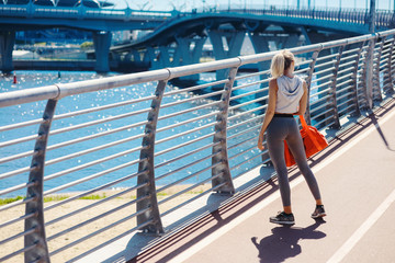 Obraz premium Young beautiful woman in sportswear. Holding a training sport bag. Going to do sports training, gymnastics in the gym. Outdoors summer fashion. Healthy sports lifestyle concept