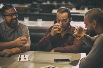 Friends spending time together in bar after work. Man in spectacles smiling and looking at his...