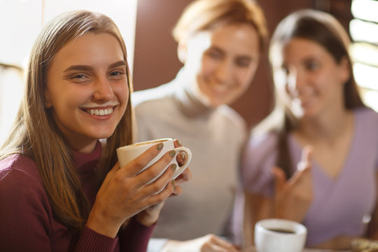 Young Girl With Coffee Foam Over Upper Lip Smiling And Looking At Camera.