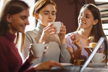 Beautiful brunette girl, gently holding cup of hot coffee at cozy cafe.