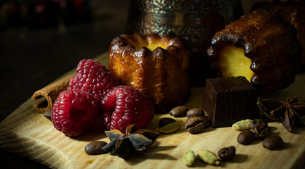 Canele, raspberry berries, chocolate and coffee beans with spices.