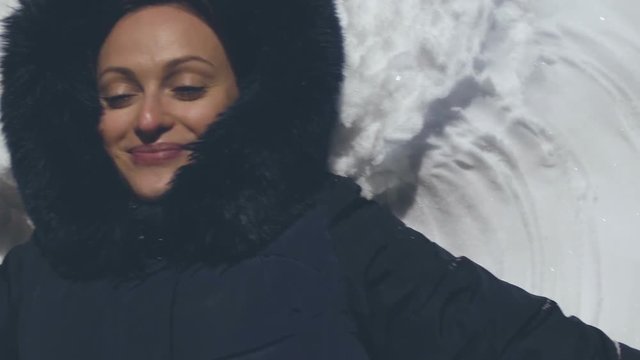 A fun girl makes an angel in the snow