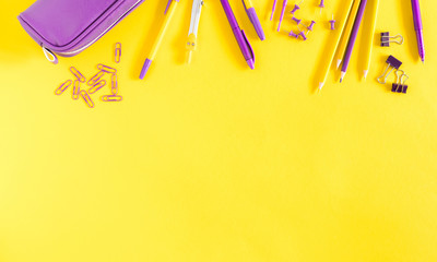 Back to school concept. Purple school supplies on yellow paper background. Flat lay, top view, copy space