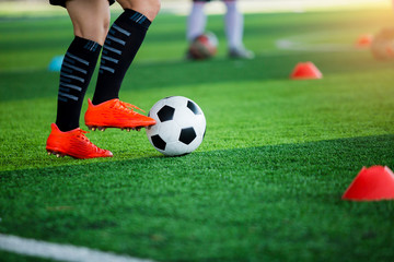 coach of soccer player standing and  stepping on the ball with blurry of young boy soccer player training.