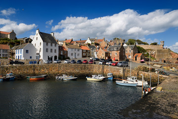 Fototapeta na wymiar Stone ramp and pier walls at Crail Harbour with fishing boats and lobster traps in Crail Fife Scotland UK