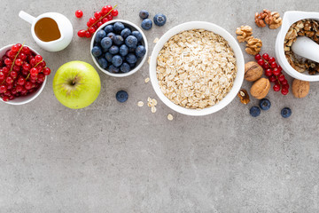 Cooking oatmeal with fresh berries, blueberry, red currant, walnuts and honey. Healthy vegetarian breakfast food concept, top view, flat lay