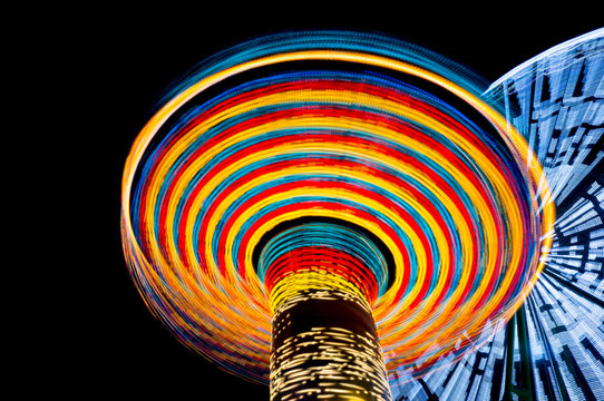 carousel and ferris wheel in an amusement park at night, long exposure. Concept of speed.