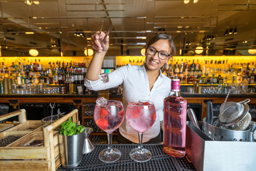 female beautiful smart bartender mixologist bar person makes prepares gin tonic cocktail drink pink...