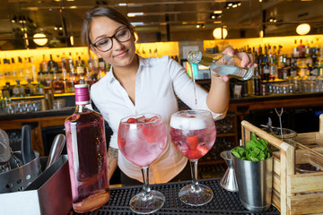 female beautiful smart bartender mixologist bar person makes prepares gin tonic cocktail drink pink...