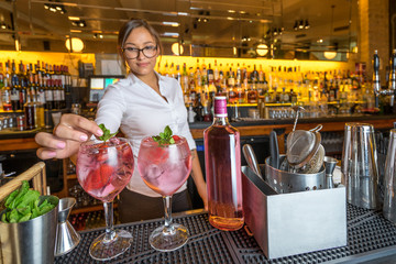 female beautiful smart bartender mixologist bar person makes prepares gin tonic cocktail drink pink...